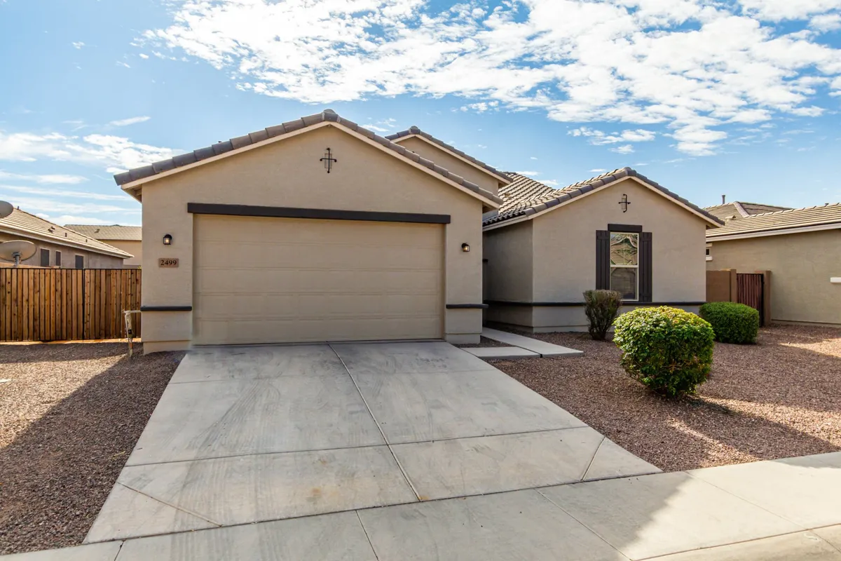 An inviting exterior shot featuring the home’s front yard, garage door, and spacious driveway. The three-car garage is clearly visible, hinting at ample storage and room for vehicles or recreational gear.