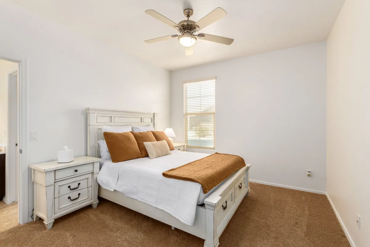 A cozy bedroom view highlighting a comfortable bed next to a sunlit window and a nightstand, creating a welcoming and peaceful ambiance ideal for relaxing or enjoying a quiet moment between work sessions.