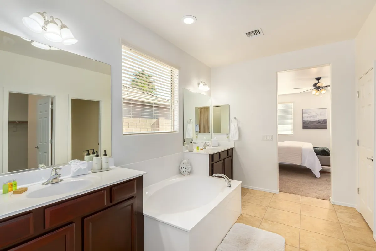 A luxurious bathroom with a prominent soaker bathtub, double sinks, expansive mirrors, and a window that fills the space with natural light. The design exudes a spa-like ambiance, inviting relaxation and self-care.