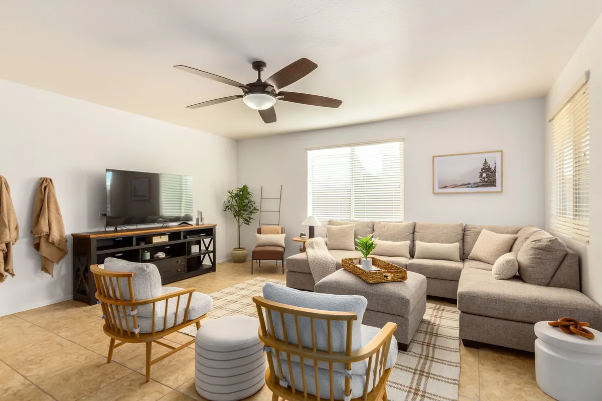 A cozy view of the living room with a plush sectional sofa, large television unit, tasteful wall art, and a touch of greenery. The setting is ideal for relaxing, movie nights, or casual gatherings.