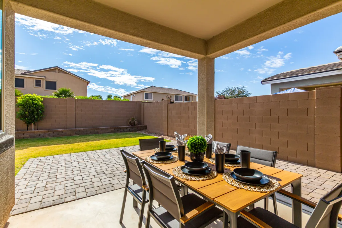 A relaxed backyard scene featuring a fenced outdoor space, a cozy dining table, and abundant greenery, ideal for barbecuing, entertaining, or simply unwinding in the sunshine.